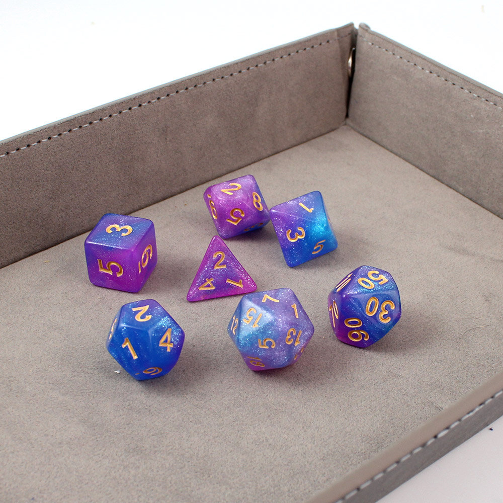 Zestaw brokatowych kości RPG Astro Dust w kolorach niebieskim i fioletowym ze złotymi cyframi.