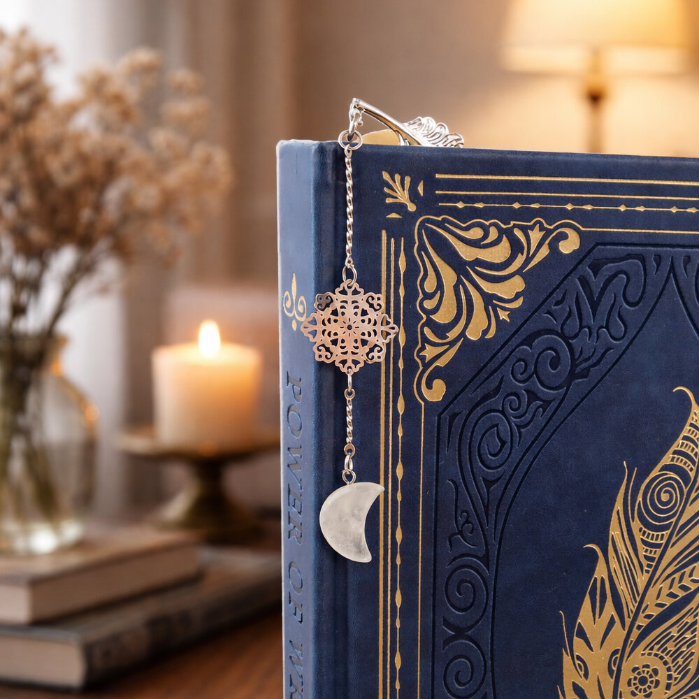 Cienka srebrna zakładka do książki pióro z zawieszką z kryształu górskiego w kształcie księżyca i ażurową rozetką w ozdobnym pudełku.