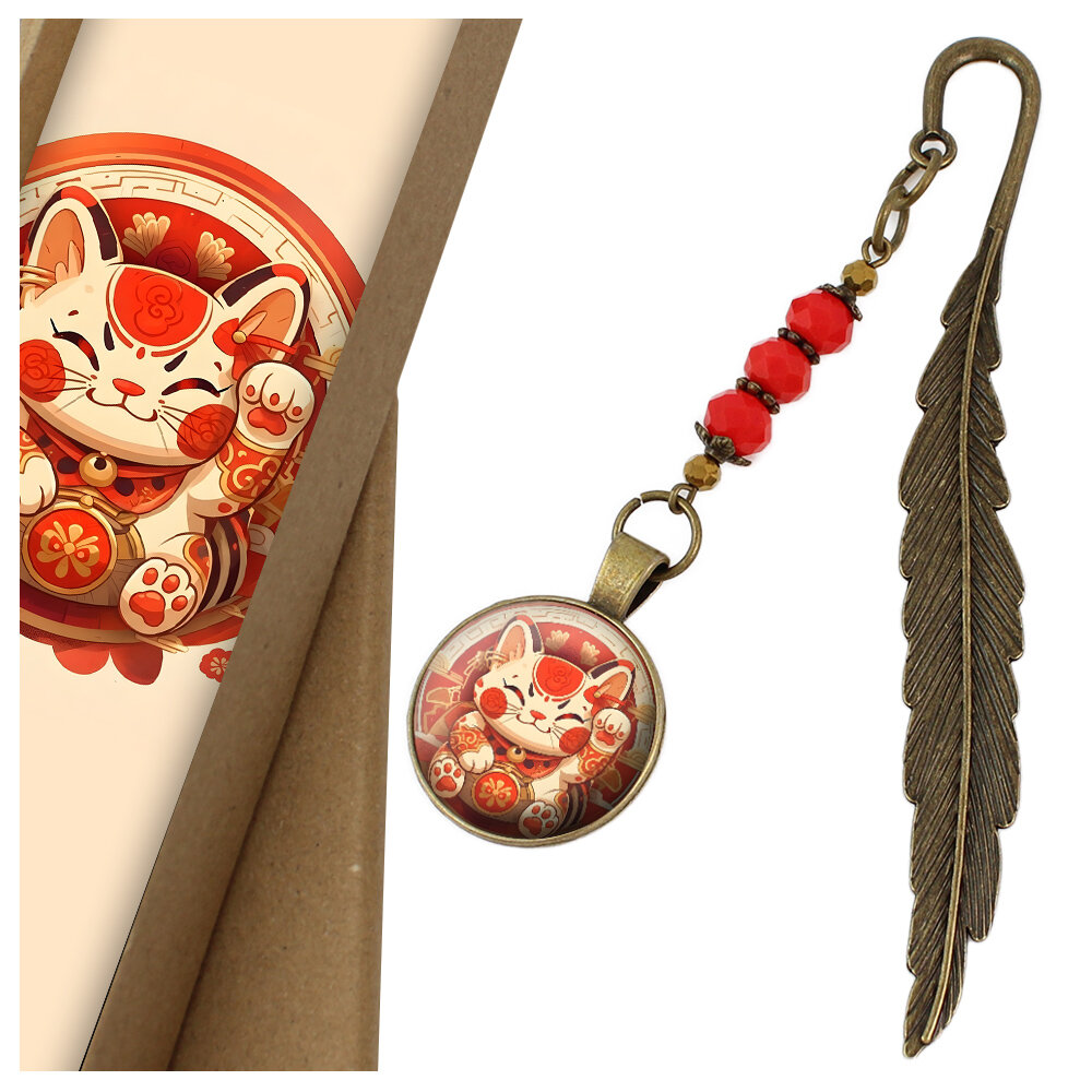 Zakładka do książki z antycznego brązu w kształcie pióra, z czerwonymi kryształkami i grafiką radosnego kota Maneki Neko pod szklanym kaboszonem.