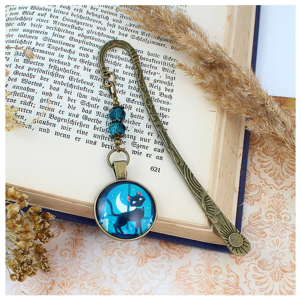 Zakładka do książki z antycznego brązu z motywem słońca i gwiazd, turkusowymi kryształkami i ilustracją czarnego kota na tle księżyca