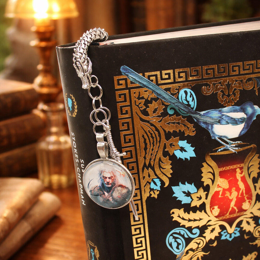 Zakładka do książki w kształcie smoka w kolorze antycznego srebra z grafiką czarownika/wojownika pod szklanym kaboszonem.