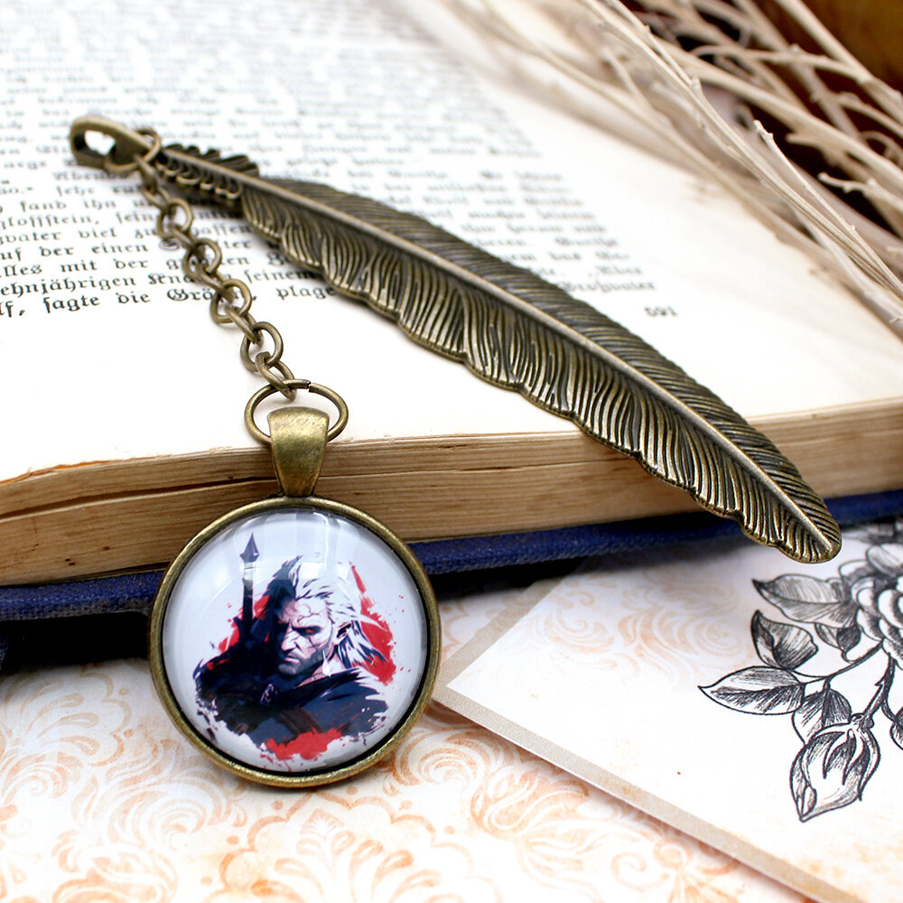 Metalowa zakładka do książki w kolorze antycznego brązu z grafiką wojownika/wiedźmina pod szklanym szkiełkiem i ozdobną zawieszką.