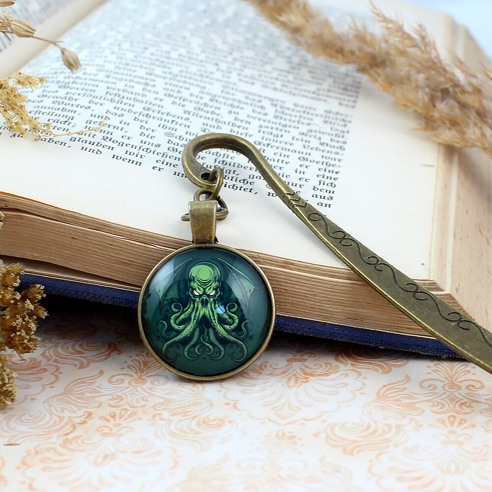 Zakładka do książki z antycznego brązu z graficznym przedstawieniem Przedwiecznego Cthulhu pod szklanym kaboszonem na tle zielonych odcieni.