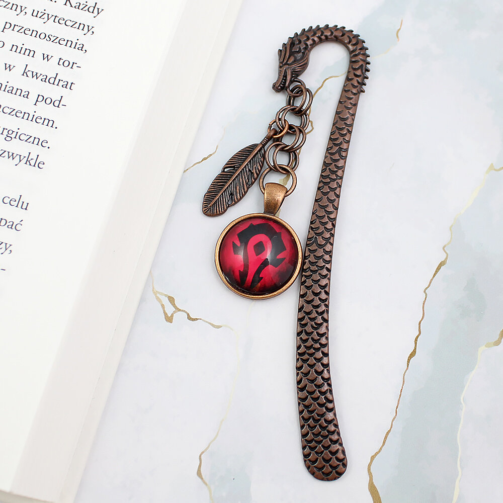 Metalowa zakładka do książki w kształcie smoka w kolorze oksydowanej miedzi z czerwoną grafiką z symbolem Hordy z World of Warcraft pod szklanym szkiełkiem oraz małą zawieszką w kształcie piórka.