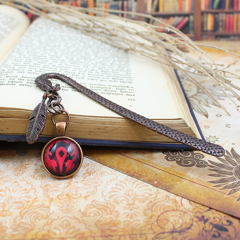 Metalowa zakładka do książki w kształcie smoka w kolorze oksydowanej miedzi z czerwoną grafiką z symbolem Hordy z World of Warcraft pod szklanym szkiełkiem oraz małą zawieszką w kształcie piórka.