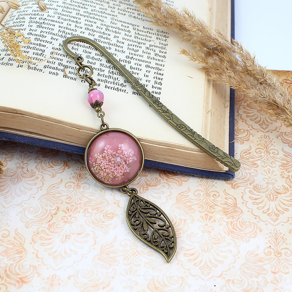 Zakładka do książki z antycznego brązu z różowym koralikiem, listkiem i uwięzionymi w różowej żywicy prawdziwymi, drobnymi suszonymi kwiatami.