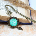 Zakładka do książki z antycznego brązu o falistym trzonie, z ozdobnym koralikiem i uspokajającą, turkusową mandalą pod szklanym kaboszonem. Zakładka do książki z antycznego brązu o falistym trzonie, z ozdobnym koralikiem i uspokajającą, turkusową mandalą pod szklanym kaboszonem.