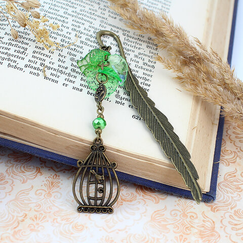 Zakładka do książki z antycznego brązu z zawieszką w kształcie ptaszka w klatce, akrylowymi listkami i szklanym koralikiem.