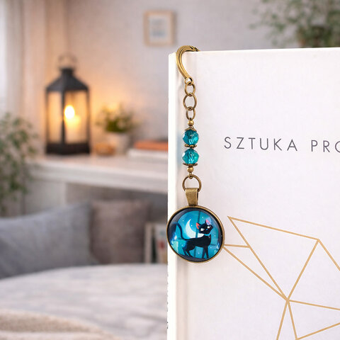 Zakładka do książki z antycznego brązu z motywem słońca i gwiazd, turkusowymi kryształkami i ilustracją czarnego kota na tle księżyca