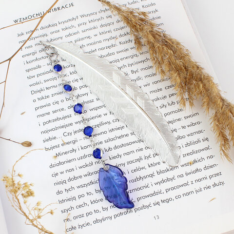 Cienka i lekka metalowa zakładka do książki w kształcie pióra, zdobiona wiszącą zawieszką z szafirowych szklanych kryształków i niebieskiego akrylowego listka, w ozdobnym pudełku. Cienka i lekka metalowa zakładka do książki w kształcie pióra, zdobiona wiszącą zawieszką z szafirowych szklanych kryształków i niebieskiego akrylowego listka, w ozdobnym pudełku.