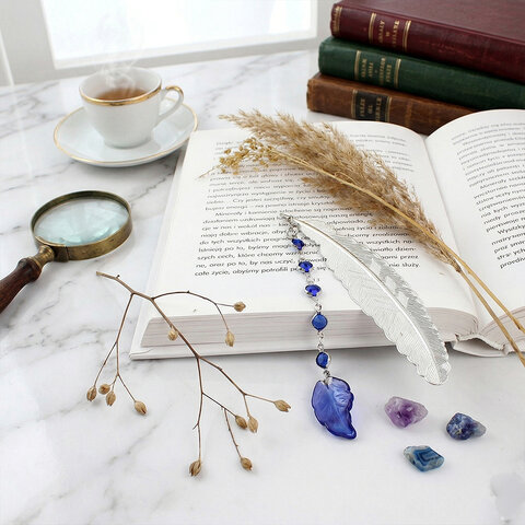 Cienka i lekka metalowa zakładka do książki w kształcie pióra, zdobiona wiszącą zawieszką z szafirowych szklanych kryształków i niebieskiego akrylowego listka, w ozdobnym pudełku. Cienka i lekka metalowa zakładka do książki w kształcie pióra, zdobiona wiszącą zawieszką z szafirowych szklanych kryształków i niebieskiego akrylowego listka, w ozdobnym pudełku.