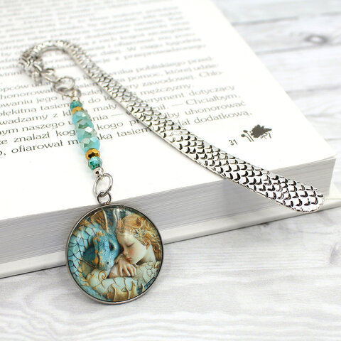 Srebrna zakładka do książki z trzonem w kształcie smoka, szklanymi kryształkami oraz zawieszką z grafiką śpiącej księżniczki i smoka Srebrna zakładka do książki z trzonem w kształcie smoka, szklanymi kryształkami oraz zawieszką z grafiką śpiącej księżniczki i smoka