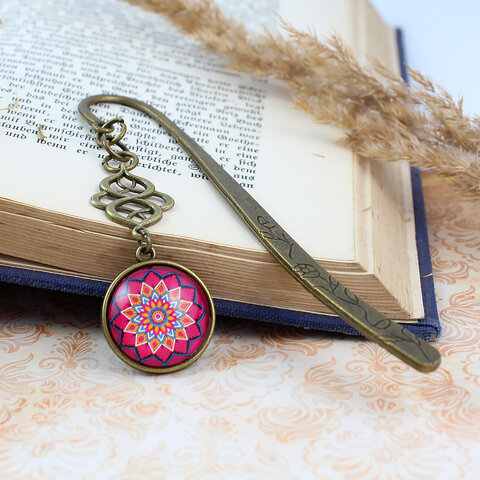 Zakładka do książki z antycznego brązu z niebieskimi koralikami i wielobarwną, harmonijną mandalą pod wypukłym szkiełkiem. Zakładka do książki z antycznego brązu z niebieskimi koralikami i wielobarwną, harmonijną mandalą pod wypukłym szkiełkiem.