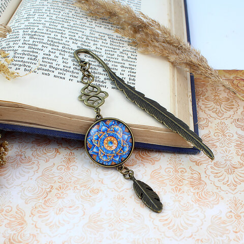 Zakładka do książki z antycznego brązu z wielobarwną mandalą o florystycznym kształcie zamkniętą pod szklanym kaboszonem na tle misternie rzeźbionej zawieszki.