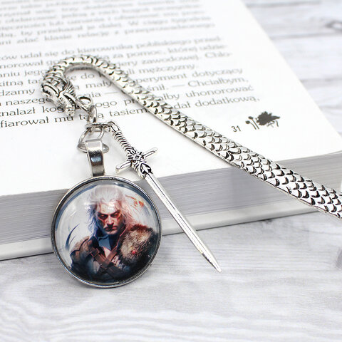 Zakładka do książki w kształcie smoka w kolorze antycznego srebra z grafiką czarownika/wojownika pod szklanym kaboszonem.