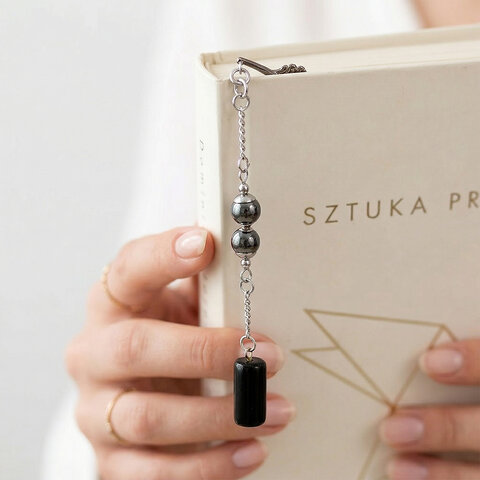 Cienka metalowa zakładka do książki pióro w kolorze grafitowym z zawieszką z czarnego onyksu i kulistego hematytu, w czarnym pudełku.