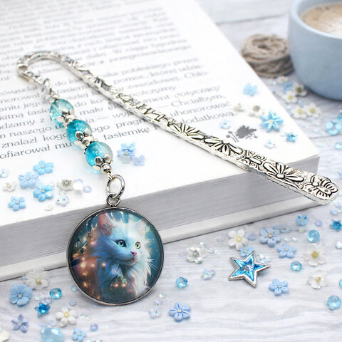 Srebrna zakładka do książki z metalowym trzonem w kwiaty i motyle, niebieskimi koralikami oraz zawieszką z autorską grafiką białego długowłosego kota Srebrna zakładka do książki z metalowym trzonem w kwiaty i motyle, niebieskimi koralikami oraz zawieszką z autorską grafiką białego długowłosego kota